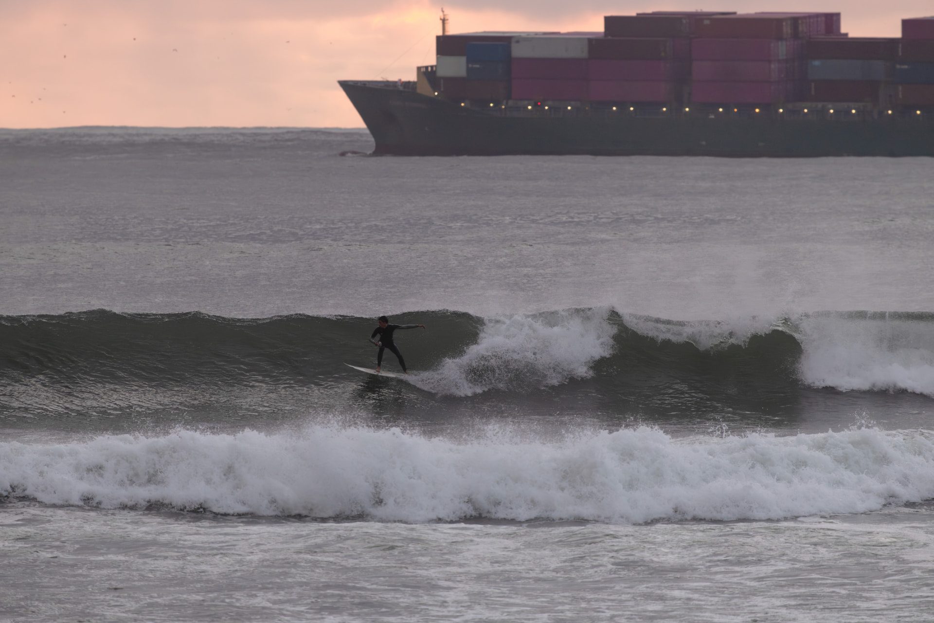 Surfer riding a wave at El Porto, Manhattan Beach, with a container ship on the horizon